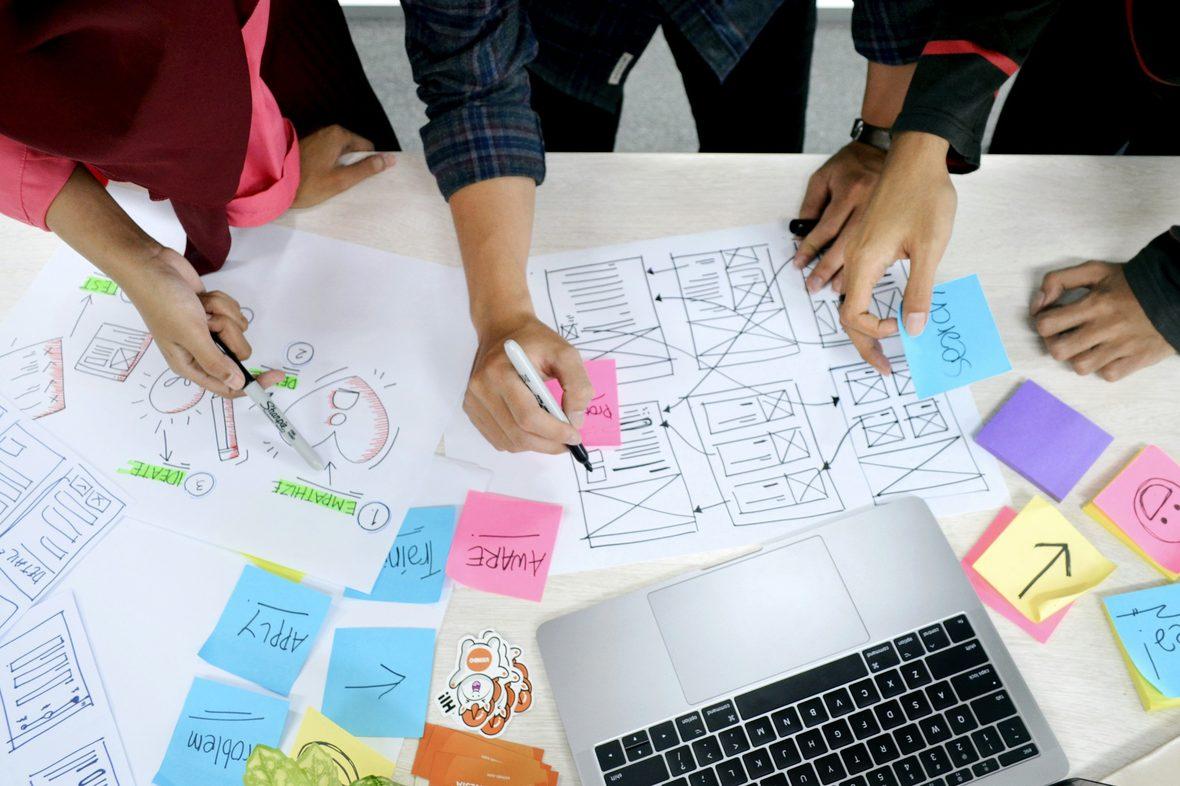 A team sketching screen layouts on paper around a table