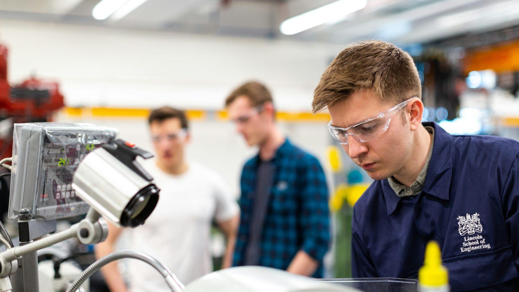 Engineers working with a robotic arm in a lab