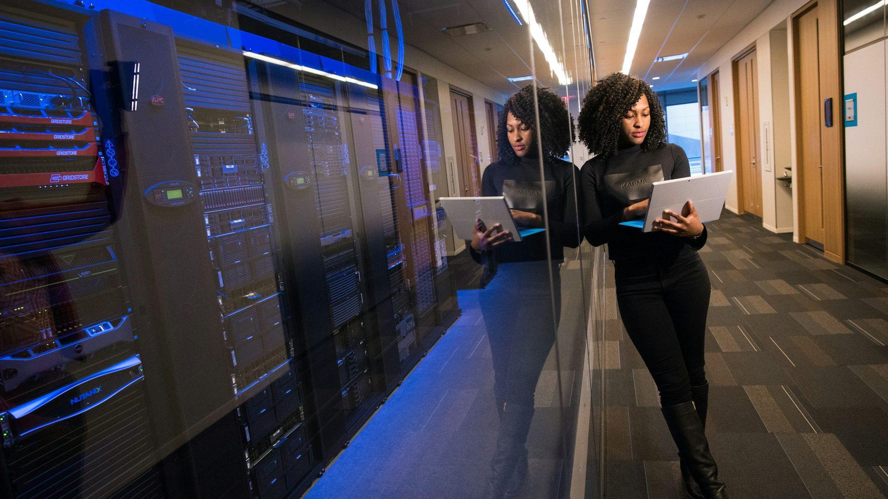 Two engineers walking a data-centre aisle with laptops