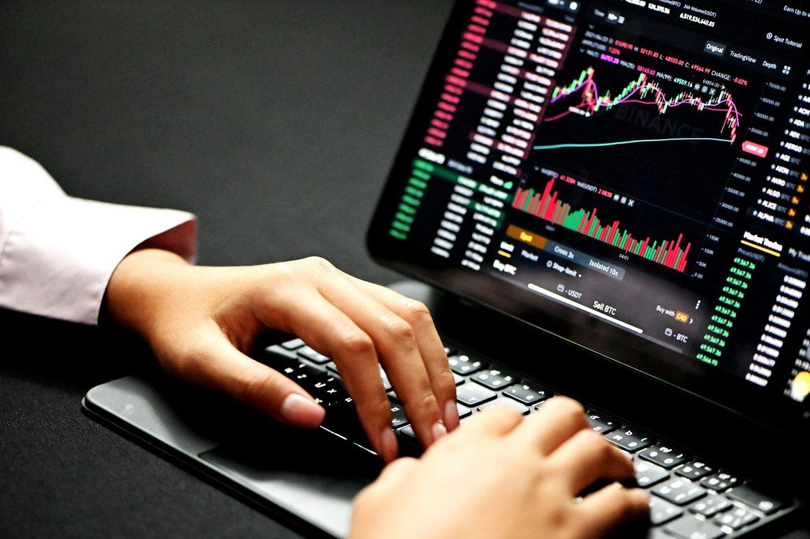 Hands typing beneath a screen of time-series charts