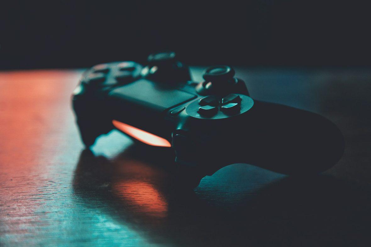 A game controller lit in colour against a dark background